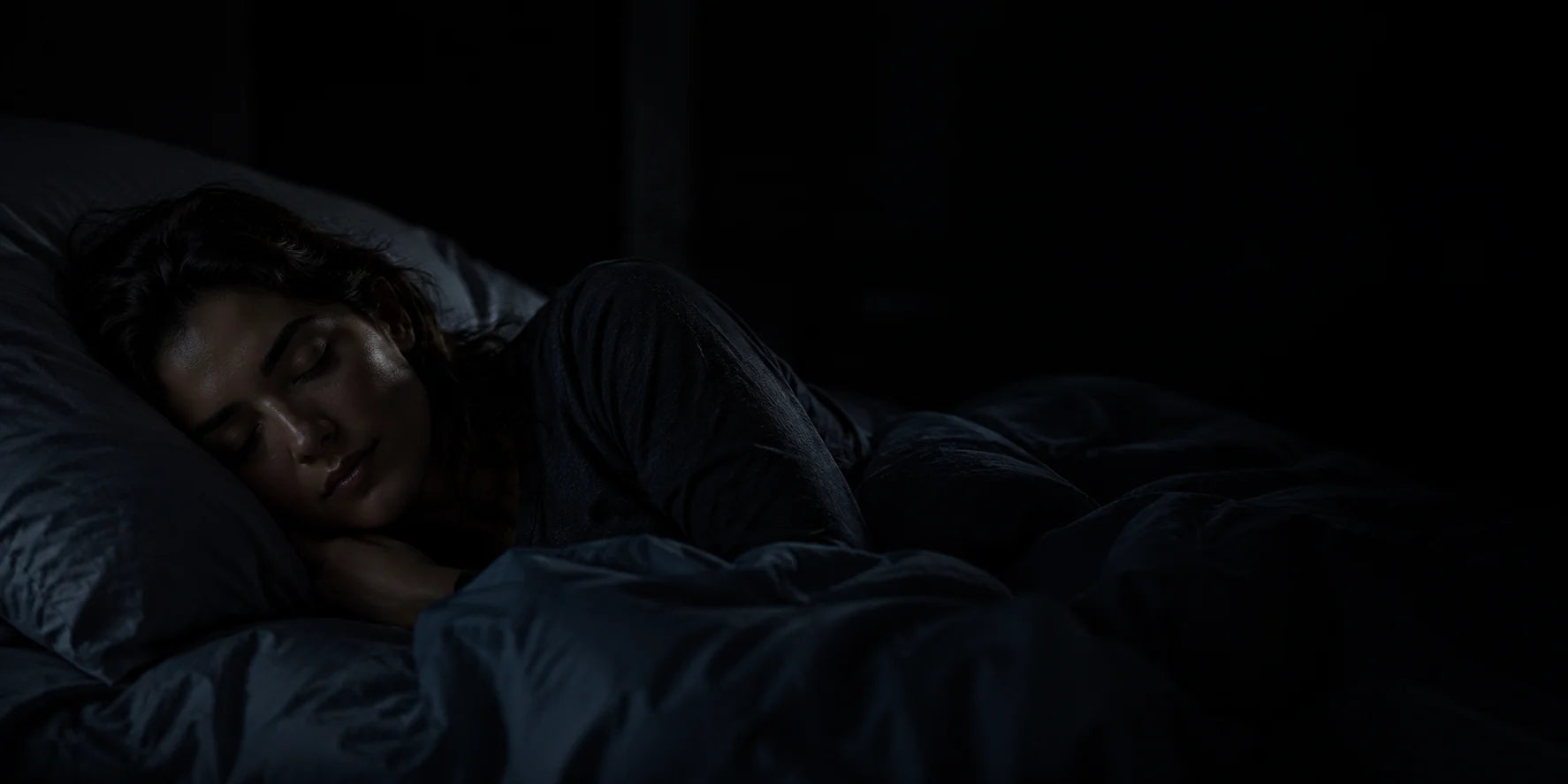 Mujer durmiendo de lado en una habitación oscura