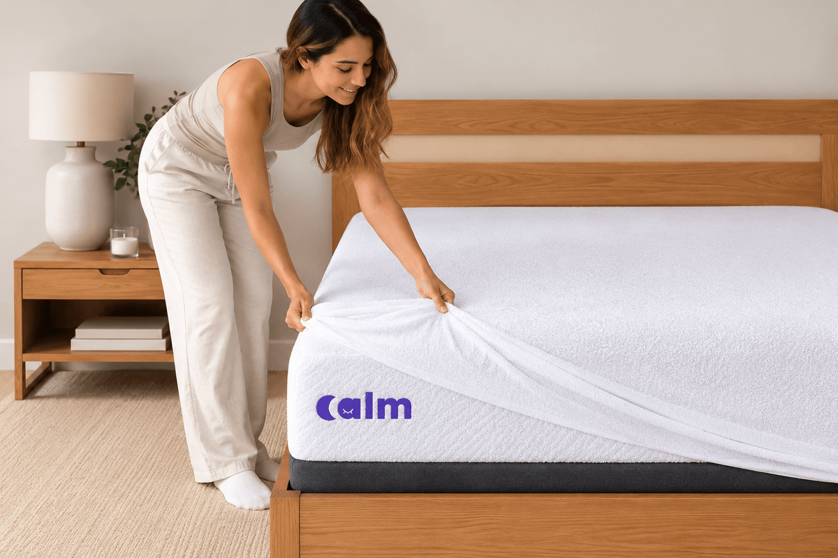 Mujer poniendo el protector Calm Shield Terry sobre un colchón Calm