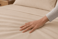 Mano alisando las sábanas Calm Microfiber color beige
